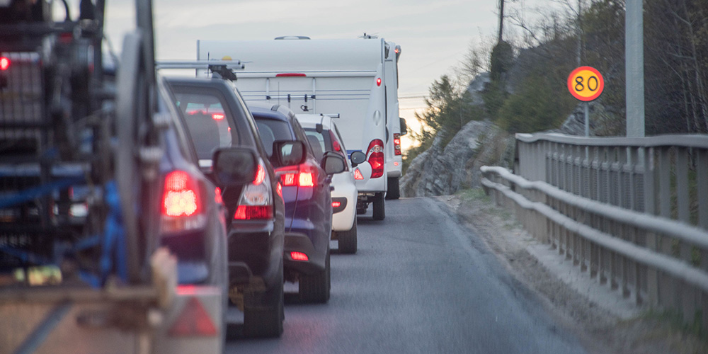 Four cars in line behind two caravans.