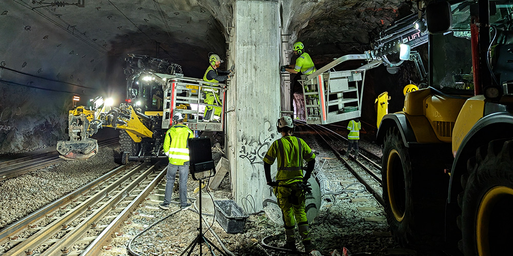 Varselklädd personal i skylift renoverar inuti järnvägstunnel.