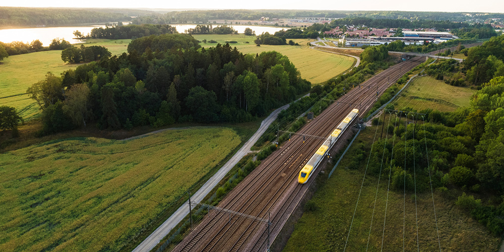 Yellow train moving through fields.