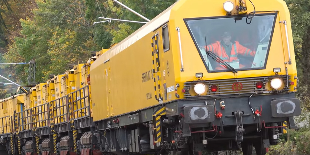 Gult tåg med varselklädd förare.