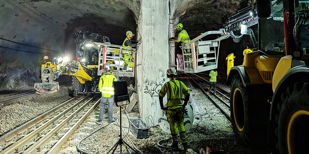 Varselklädda personer arbetar med hjälp av skylift i en järnvägstunnel.