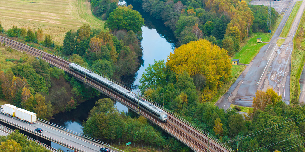 Drönarbild över Järnvägsbro och vägbro över vattendrag.