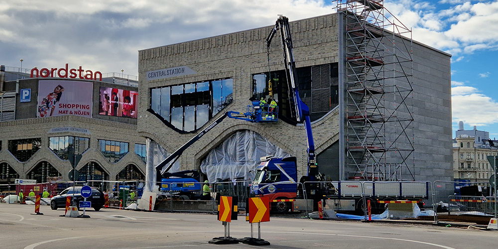 Fyrkantig stenbyggnad med stora fönster. Till vänster syns gallerian nordstan.