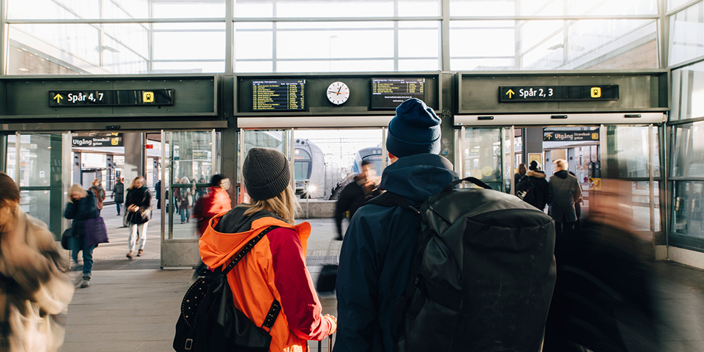 Tågresenärer på station tittar på trafikinformation.