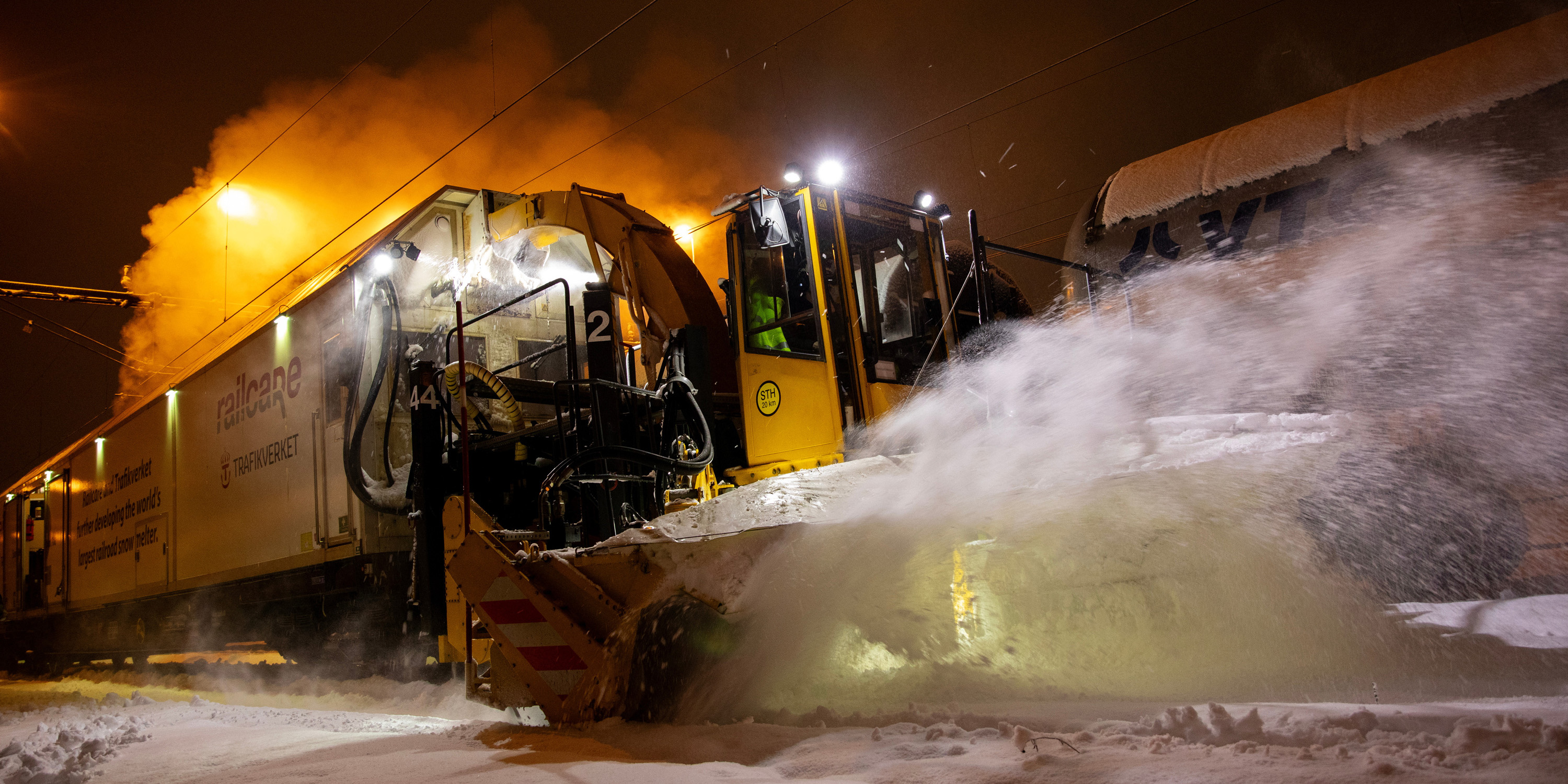 Snösmältningståg borstar bort snö från spår nattetid.